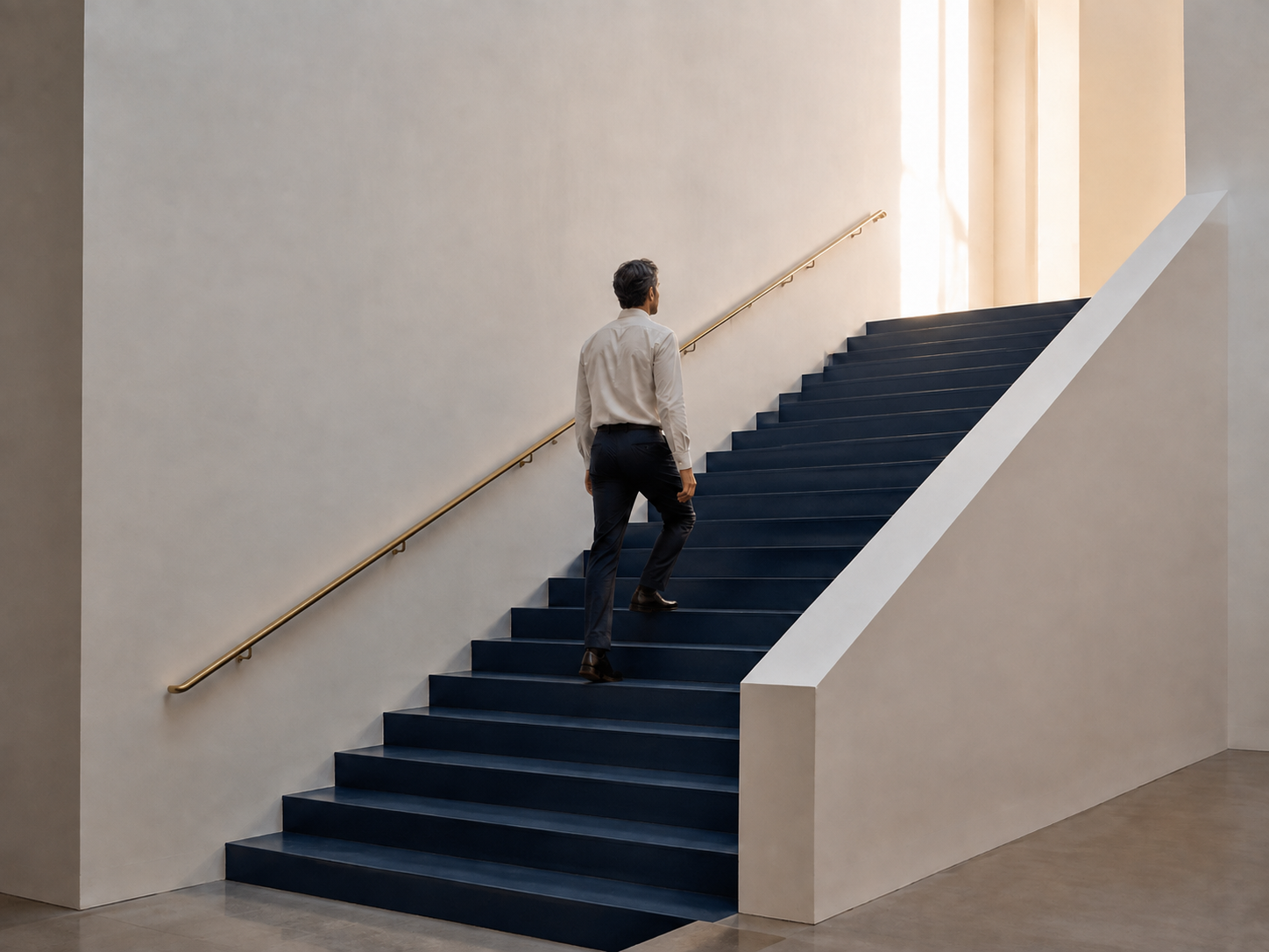 A man ascending a navy stairway toward warm daylight